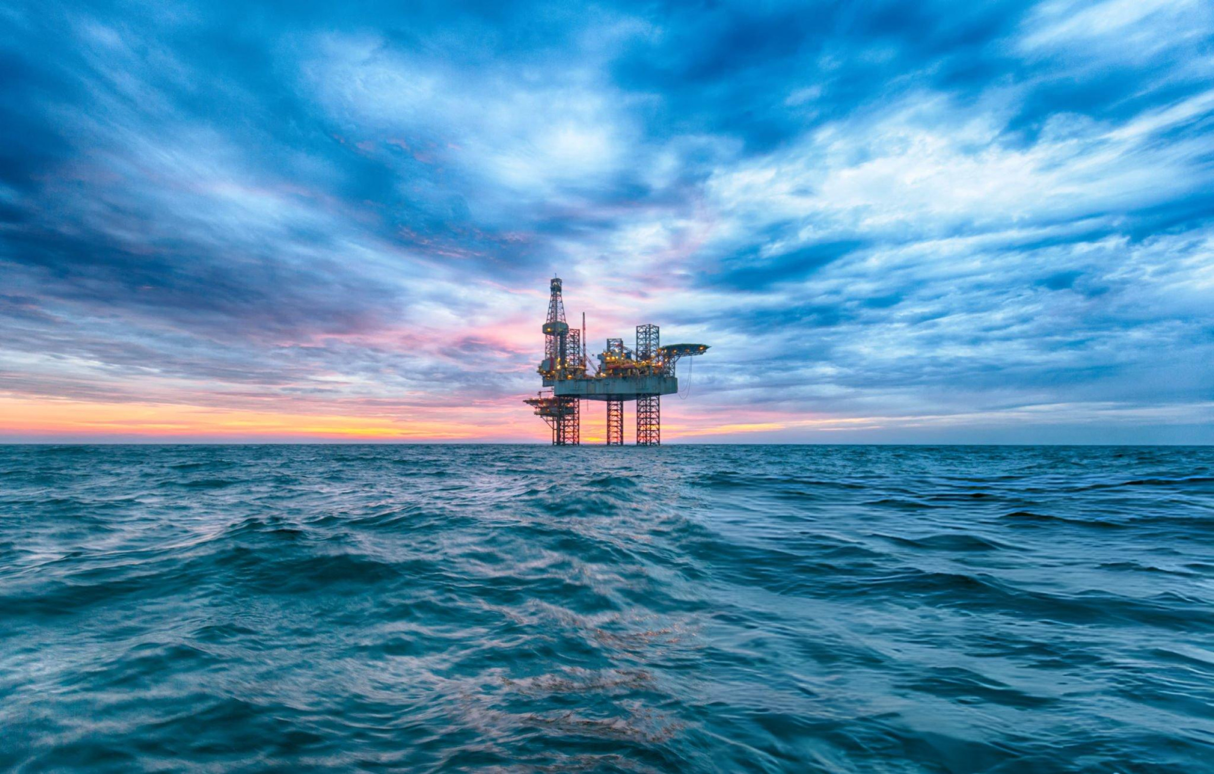 Offshore drilling rig at sea at sunset